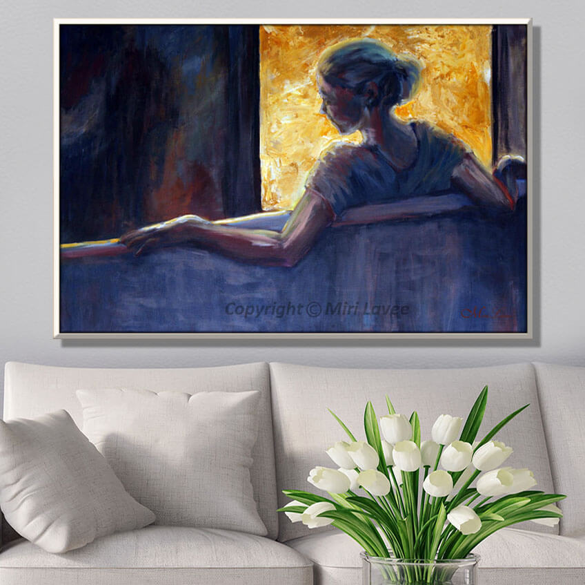 ציור דמות אישה בגוונים כחולים יושבת מול חלון מואר, תמונה מעל ספה בסלון לבן, ציירת מירי לביא