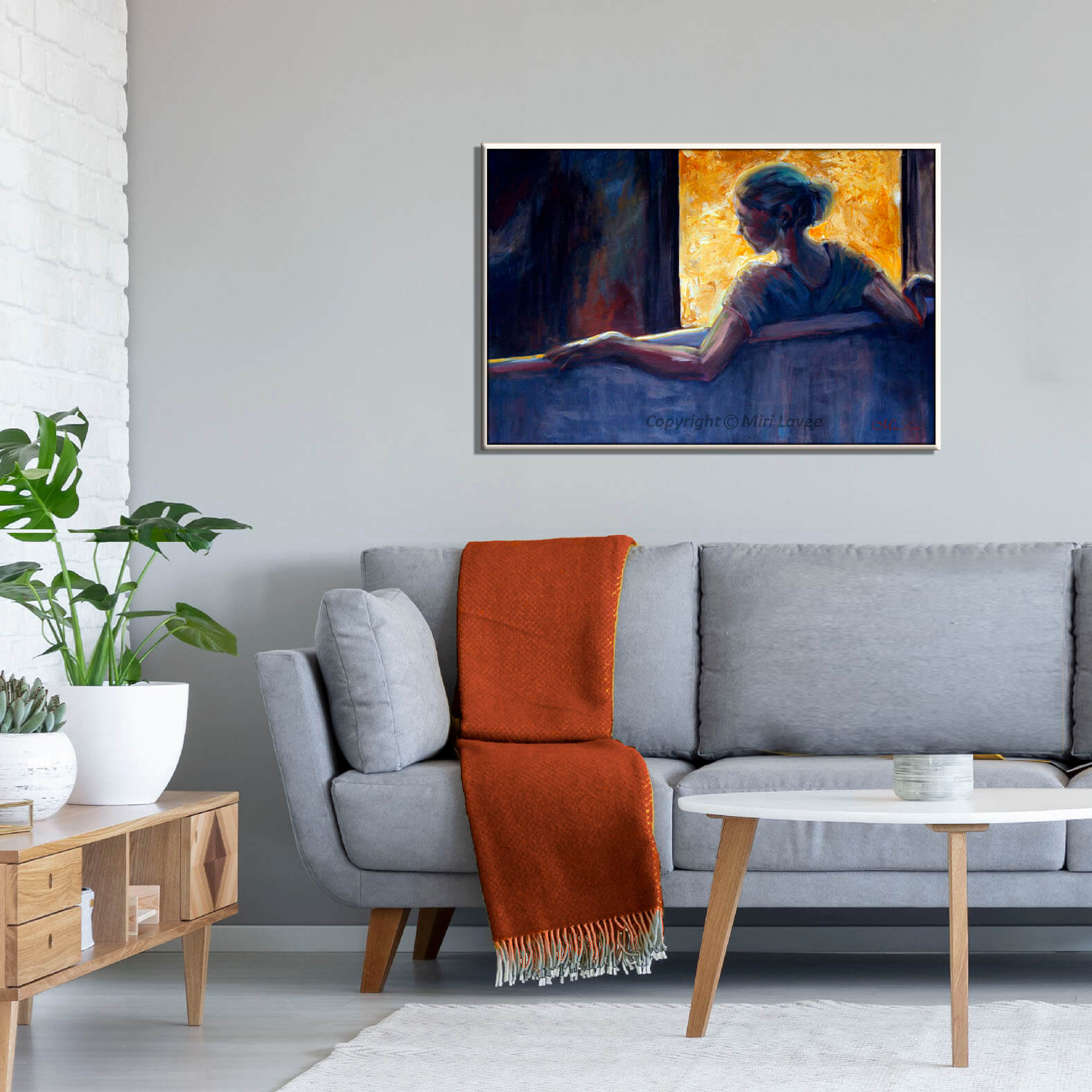 ציור דמות אישה בגוונים כחולים יושבת מול חלון מואר תמונה בסלון מעל הספה ציירת מירי לביא